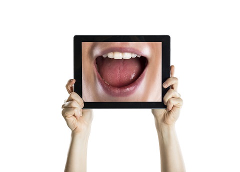 A lady looking at her smile using a tablet