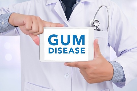 Man holding a sign with gum disease on it