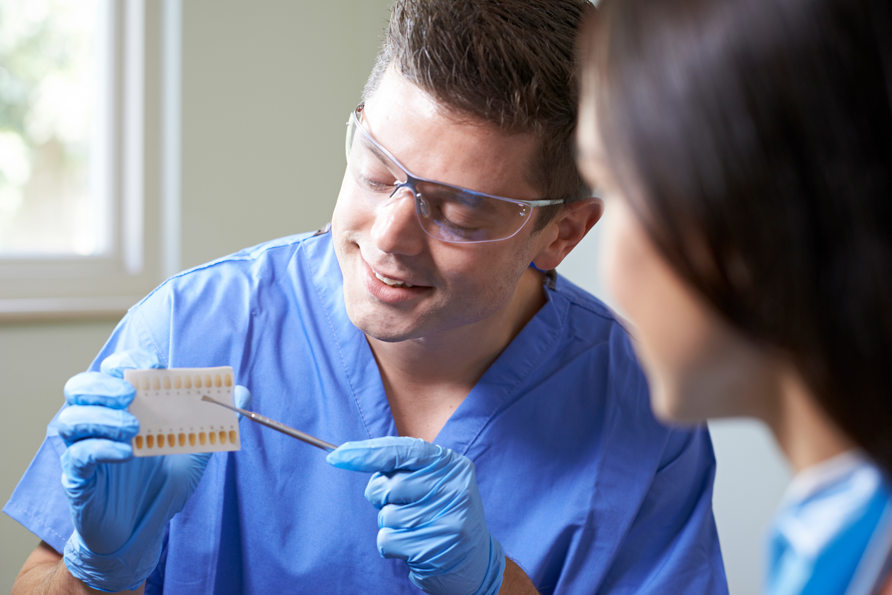 A dentist showing his patient the different shades of white