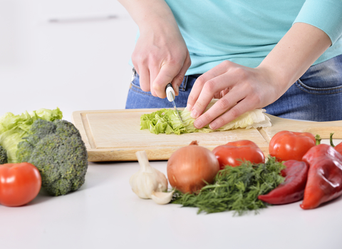 A person cutting up fresh vegetables