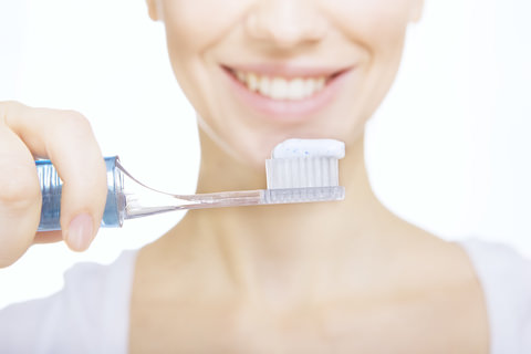 A lady brushing her teeth with toothpaste