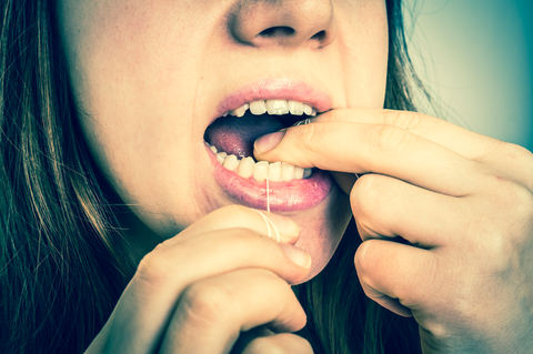 A lady using floss to get inbetween her teeth