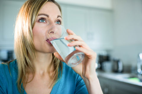 A lady rinsing her mouth out with a glass of water
