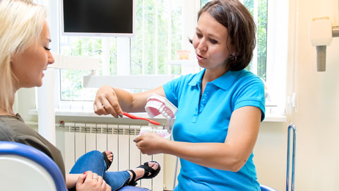 A hygienist showing a patient how to brush their teeth