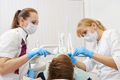 An orthodontist and dental assistant inspecting crooked teeth