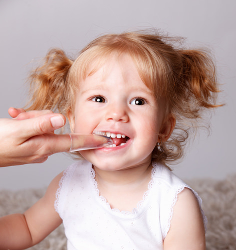 A parent cleaning their toddler's teeth