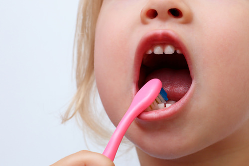 A girl brushing her teeth on her own