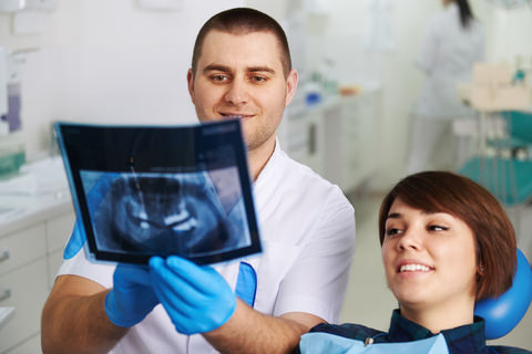 A dentist looking at a patients dental X-Ray