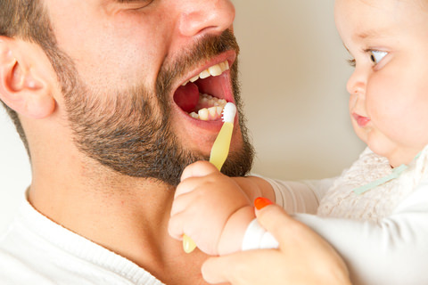 A baby brushing her dads teeth