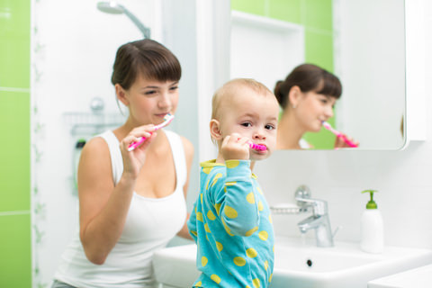 A parent teaching their child to brush his teeth
