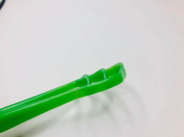A side, raised view of the The triple cleaning function of the GOOD Tongue Cleaner