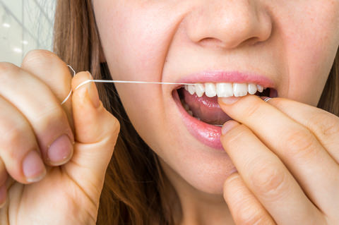 A lady showing how to floss your teeth