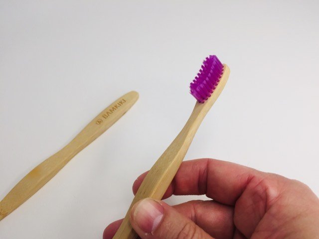 holding the handle of the bamkiki bamboo toothbrush