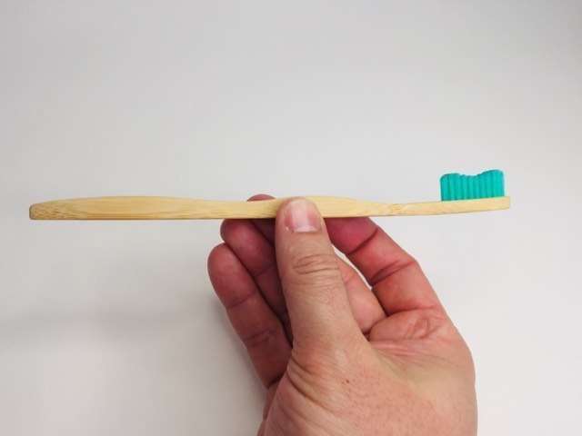 Holding the roxo colour bamkiki bamboo toothbrush
