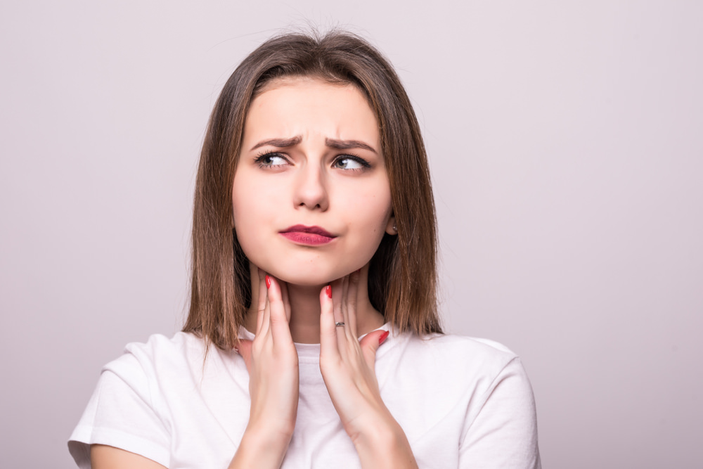 A woman with a worried face holding her throat