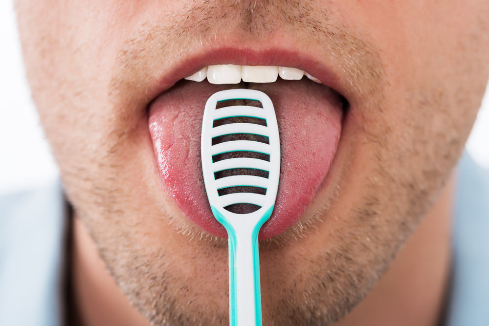 A man using a tongue scraper