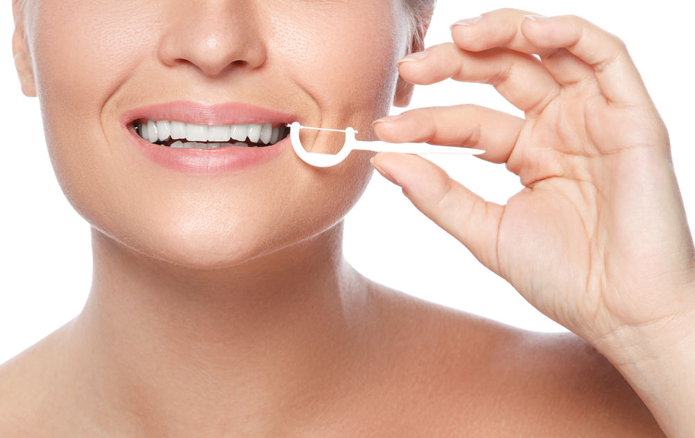 A lady using Dental floss picks