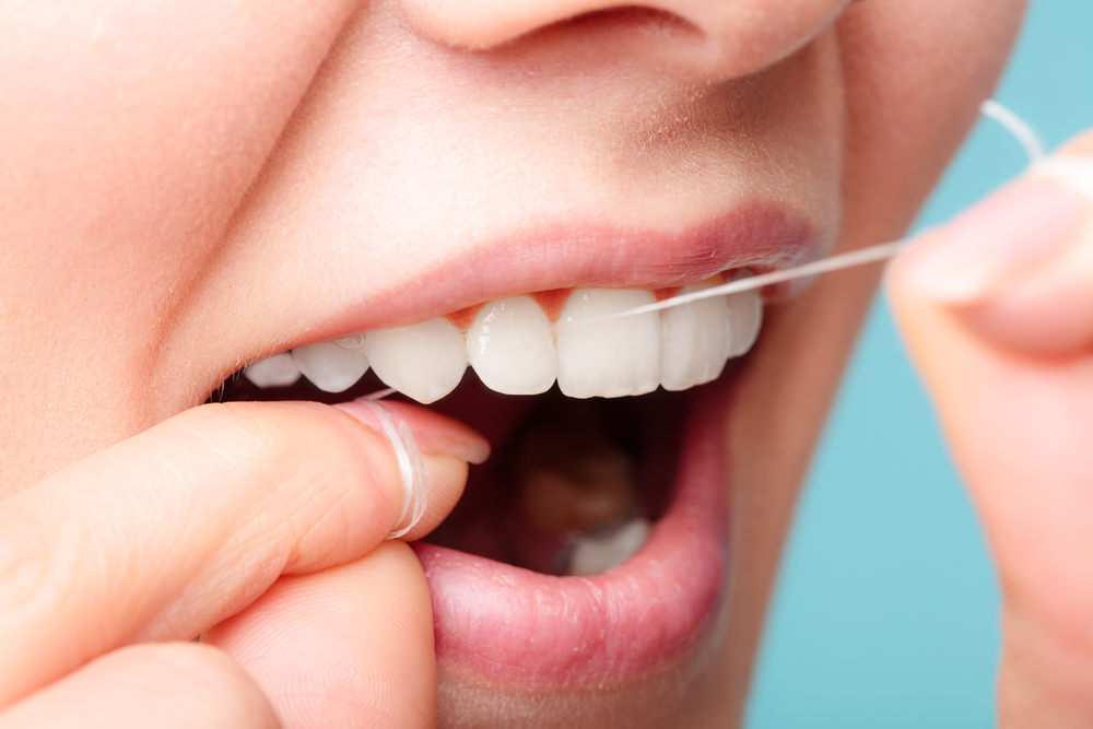 A lady flossing her teeth