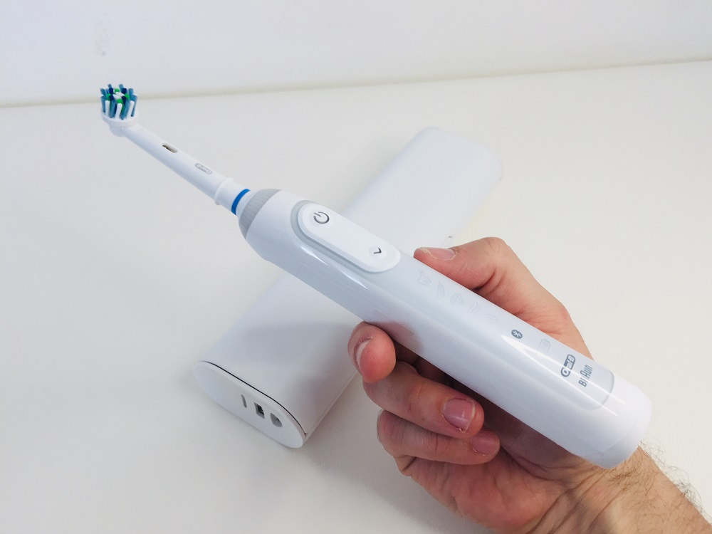 holding the Oral-b Genius 9000 electric toothbrush