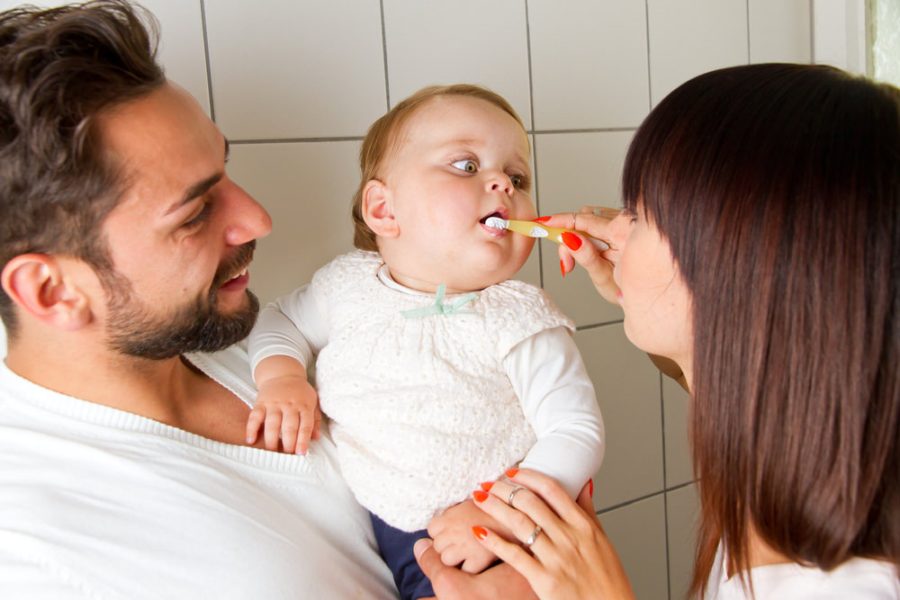 Parents working together to brush their babys teeth