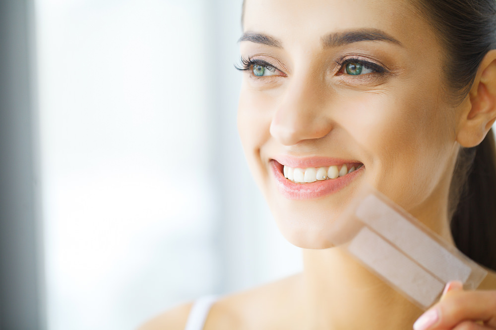 A lady holding some teeth whitening strips