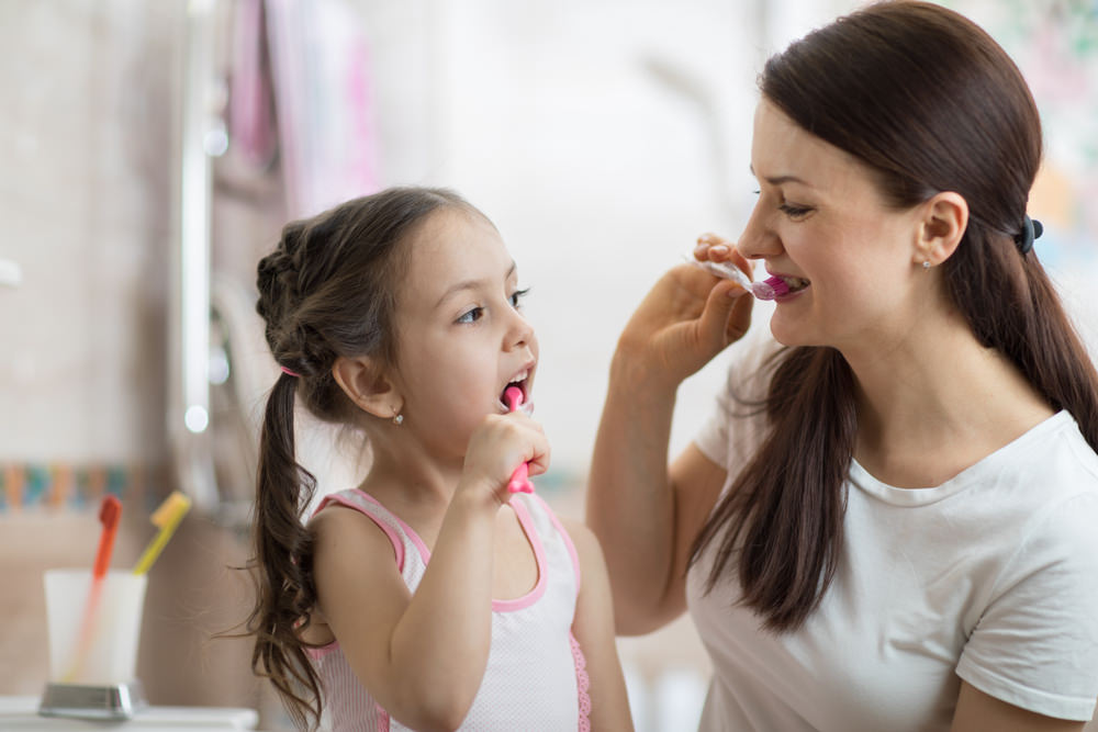 A mum and her child brushing their teeth together