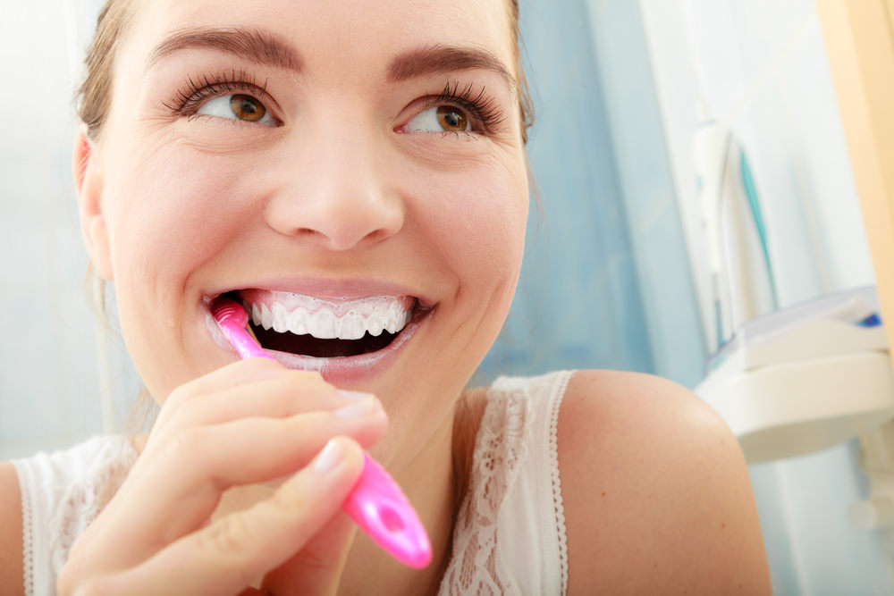 A lady brushing her teeth with toothpaste and a toothbrush