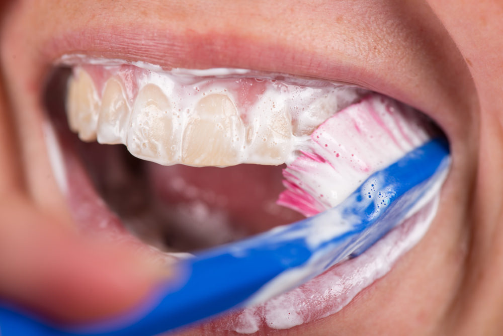 a person brushing their teeth with a toothbrush and toothpaste