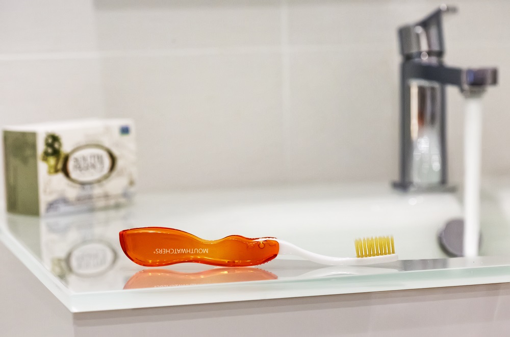 Orange Mouthwatchers Travel Toothbrush on a bathroom sink